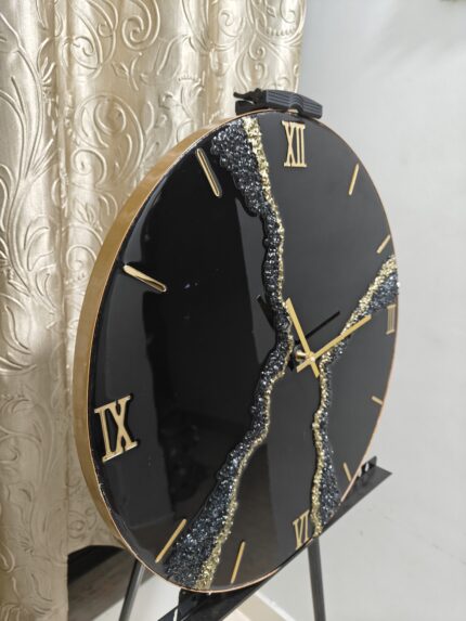 "A stylish resin wall clock featuring a black and gold color palette, perfect for modern and luxurious interiors."