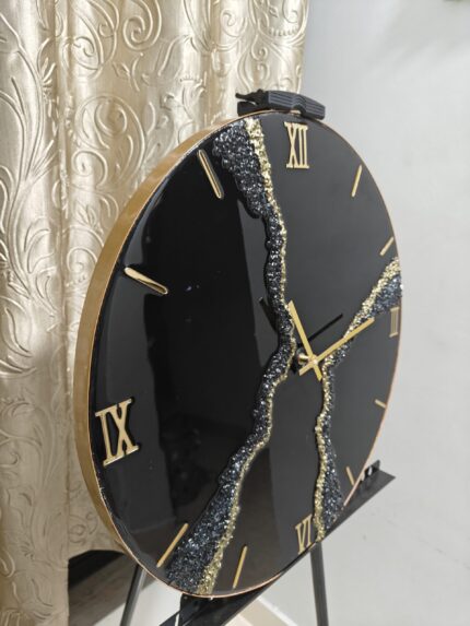 "A stylish resin wall clock featuring a black and gold color palette, perfect for modern and luxurious interiors."