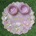 "A 10-inch resin pooja platter with intricate designs, glossy finish, and compartments for pooja essentials like diya and incense."