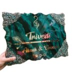 Luxury emerald green and teal marble resin nameplate with gold textured edges, featuring Om symbol, flute and feather design